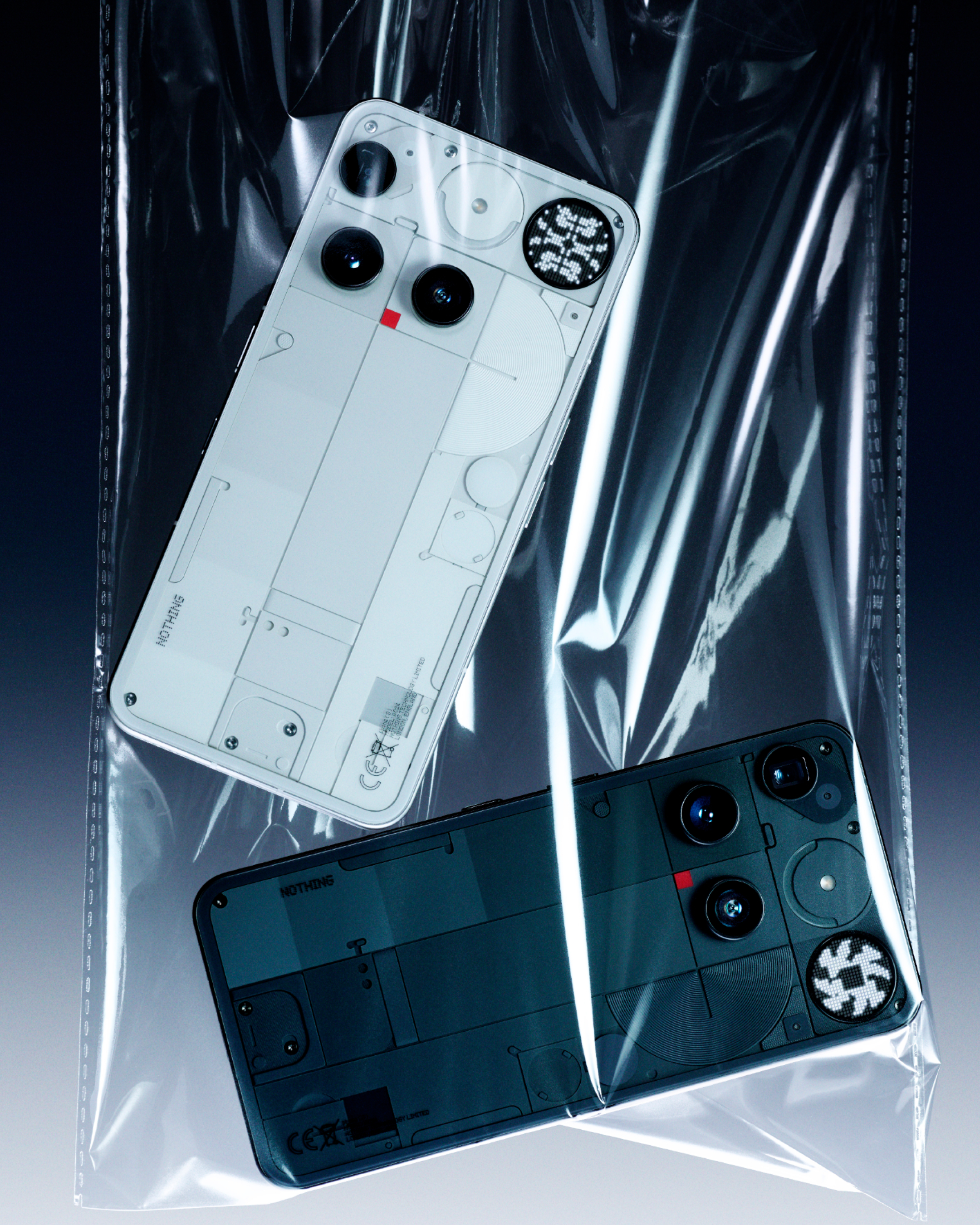 Zwei Nothing Phone (1) Smartphones, weiß und dunkelgrau, in einer durchsichtigen Plastiktüte. Telefonkameras sichtbar.